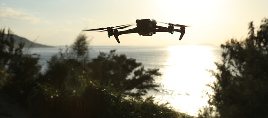 Silhouette of flying drone taking photo over sunrise