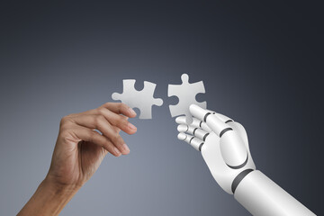 Human hand and Robotic hand holding puzzle on dark background, collaboration and innovation concept.