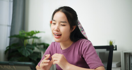 Portrait of Young asian businesswoman sitting at desk and having a video call meeting on digital tablet at home office, online meeting for remote work