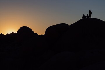 Silouette of poeple standing on giant boulders in Joshua Tree National Park, California, United States of America.