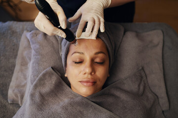 Calm woman visiting cosmetologist to get beauty procedure, top view