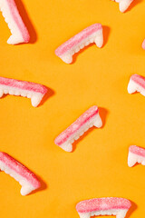 Creative Halloween background with gummy vampire teeth candy on bright orange background