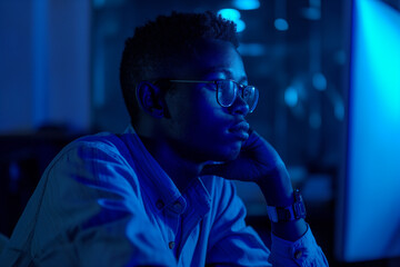 Dedicated man working late into the night, bathed in blue light. His intense focus and serene expression highlight his commitment and perseverance