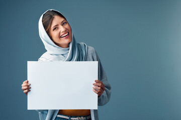 Sign, portrait and islam woman in studio, smile and advertising on blue background for promo. Mock...