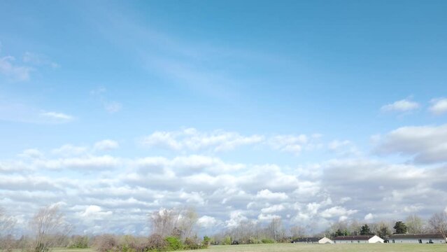 Rolling beautiful white and gray puffy clouds background behind a green forest and suburban neighborhood