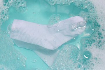 Cleaning dirty socks in basin of soapy water