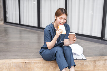 Obraz premium A young Asian female nurse relaxes outdoors, sitting after work.
