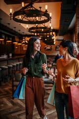 Women entering a restaurant, smiling and engaging in lively conversation with shopping bags from their day out