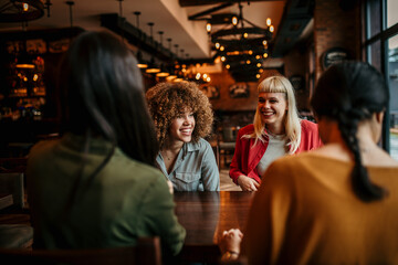 A multiracial group of young people sitting in a coffee shop and smiling