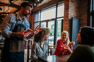 Young women smiling, talking and ordering to waiter at the cafe restaurant