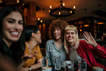 Four female friends sitting in the cafe and taking a selfie