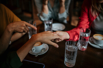 An unrecognizable woman showing an engagement ring to her female friends. Focus on hands