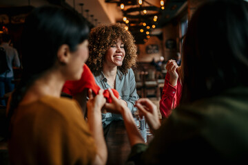 Female friends sitting in the cafe and chatting about new clothes that they bought