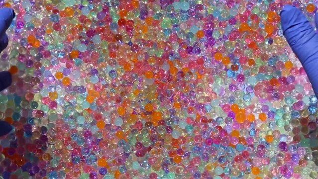 Hands slowly move a lot of small, colored, shiny balls. The fingers dip into the multicolored orbis and gently lift up. Asmr. Part 6.14