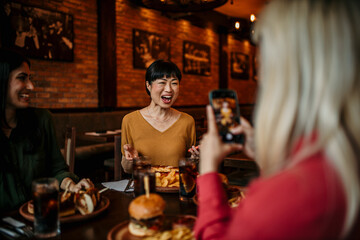 Group of female friends taking photos of food in the restaurant before eating. People and social media concept