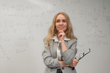Fototapeta premium A Caucasian woman stands at a blackboard with written formulas.