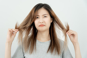 Asian woman very sad and upset looking at damaged hair, hair loss, hair thinning problem, vitamin...
