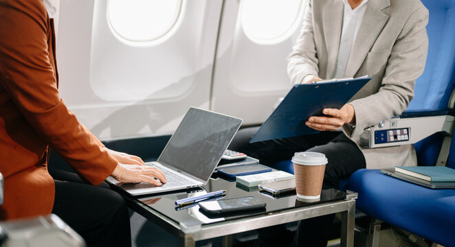 Business meeting in airplane, asian Mature businessman in private jet is talking with Mature female colleague and documents, business people flying in airplane