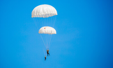 Skydiving. Flying parachutists against the background of the blue sky and mountains. Extreme sport and entertainment.