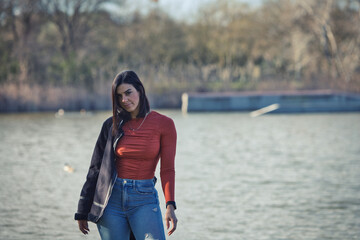 Young, beautiful brunette woman, with short hair and jeans and orange shirt with jacket over her...