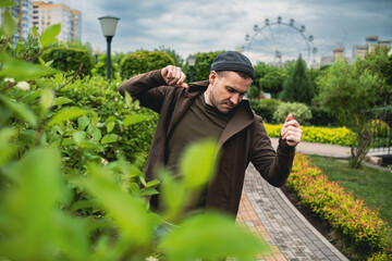 Handsome Man Dancing Enthusiastically in a Lush Green Park on a Cloudy Afternoon