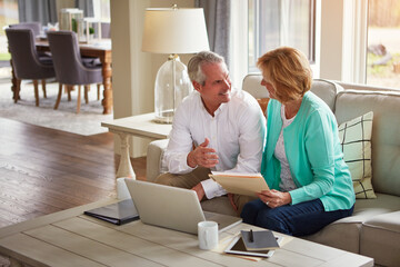 Senior couple, paperwork and finance on couch with laptop, smile or check for taxes in home. Old man, woman and computer with documents for compliance, audit or investment report for budget review