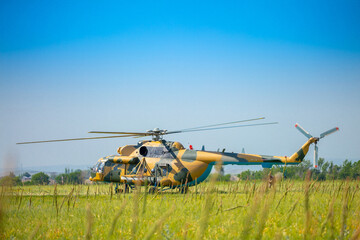 In the field is a military helicopter with soldiers. Armed conflict, fighting. Air armament and...