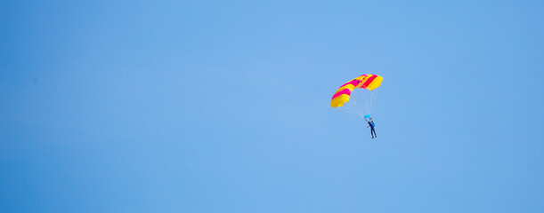 Skydiving. Flying parachutists against the background of the blue sky and mountains. Extreme sport and entertainment.
