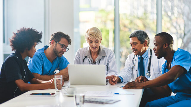 Medical team, laptop and meeting in office for healthcare, research and expertise in hospital. Men, women and feedback at table for brainstorming, consulting and problem solving in boardroom