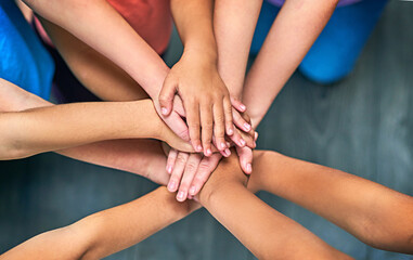 Children, hands together and solidarity for support, trust and achievement for education. Students, kids and collaboration for teamwork, success and development with huddle for commitment by above