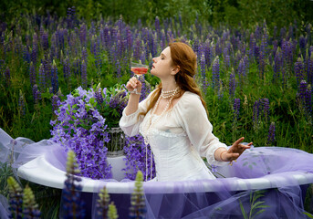 beautiful romantic readhead bride in vintage white wedding dress sitting in bath the field of...