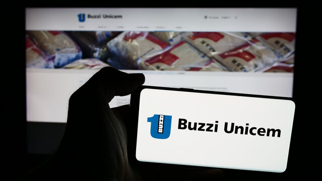 Stuttgart, Germany - 06-01-2024: Person holding mobile phone with logo of Italian building materials company Buzzi Unicem S.p.A. in front of web page. Focus on phone display.