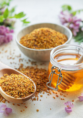 Raw organic bee pollen and honey in jars  and acacia flowers. .