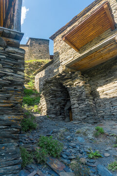 A narrow street between the walls and dooway of houses. Wooden balconies. Medieval village Mutso.