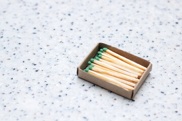 There is a rectangular box of matches with green tips placed on a table