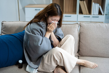 woman sitting on sofa covered with blanket freezing blowing running nose got fever caught cold...
