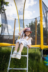 backyard playground. happy child sitting on trampoline in summer outdoor. Kids fun.