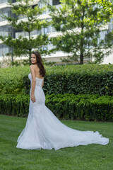 Beautiful young bride in white wedding dress posing outdoor in the park