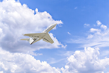Private business plane flying under a blue sky with white clouds