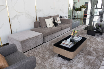 Interior of light living room with brown, grey sofas, coffee table and large window