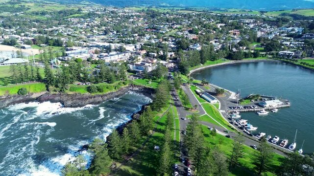 Aerial drone landscape of Kiama main town rural suburb city harbour bay foreshore with cars on street housing shops residential living South Coast Gerringong Australia