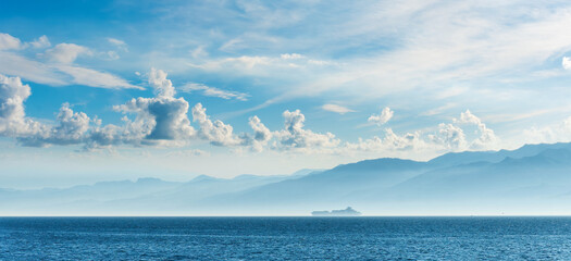 tropical seascape of sailing kargo tanker ship in sea with beautiful sunset and mountains on...