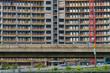 A detailed view of a high-rise building under construction with scaffolding and a crane