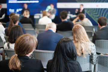 Fototapeta premium A diverse audience attentively listening to speakers during a professional business seminar or conference in a modern setting.