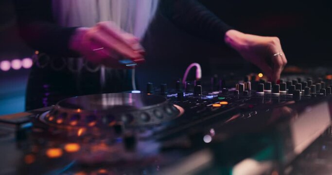Close Up of an Anonymous Female DJ Performing Live at a Night Club, Using DJ Turntable Decks and Mixer to Play Techno Dance Music at a Rave Party. Pop Music Beats at an EDM Concert on Stage