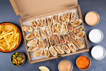 Turkish or Arabic Shawarma box full of pieces of chicken shawerma or shawarma wrap with onion, tomato, lettuce and garlic sauce in Syrian bread with side french fries and fried bread.