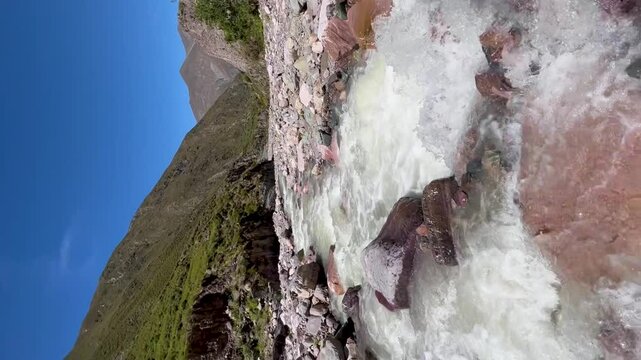 Mountain stream flows through rocky terrain in Iruya, Argentina, vertical shot, clear blue sky