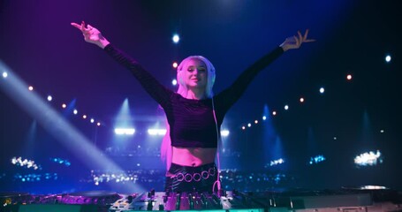 Beautiful Female Disk Jockey Energetically Performing at Nightclub, Surrounded by Dancing Music Lovers. Pop Idol Creating a Unique Show Experience with Dynamic Visuals and Powerful EDM Music