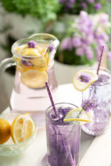 Jug and glasses with lavender lemonade  and ice in a tray on a background of flowers