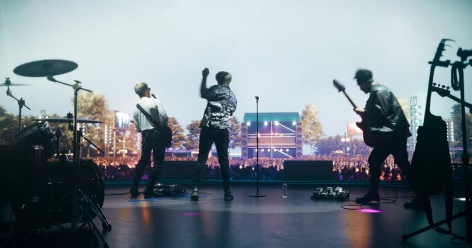 Indie Rock Band Delivers a Mesmerizing Live Performance With Guitars and Drums at a Massive Open Air Concert. Colorful Lights and Powerful Sound Play at a Rock Festival. Footage From the Back